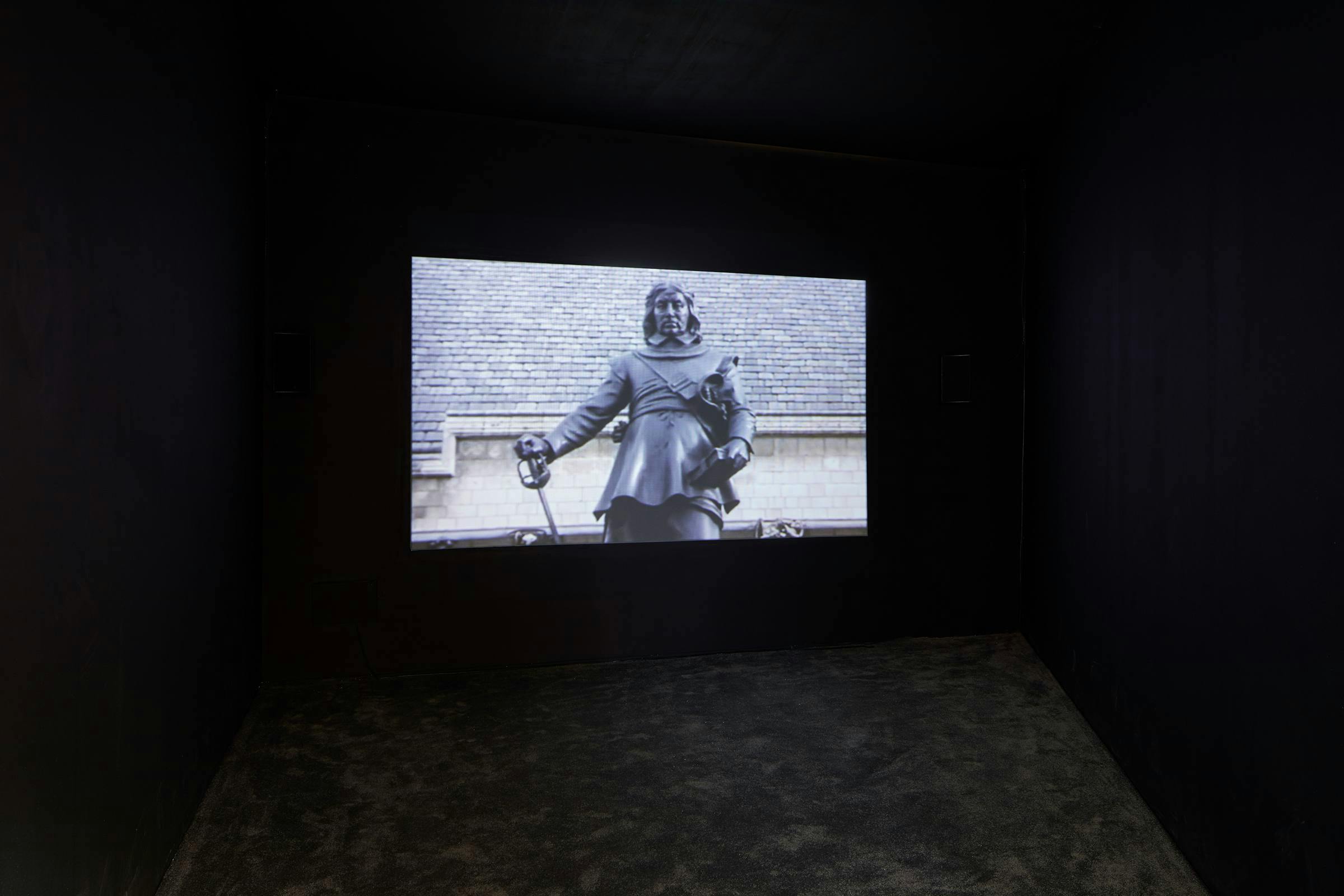 Image of a film being shown in a darkened gallery space.
