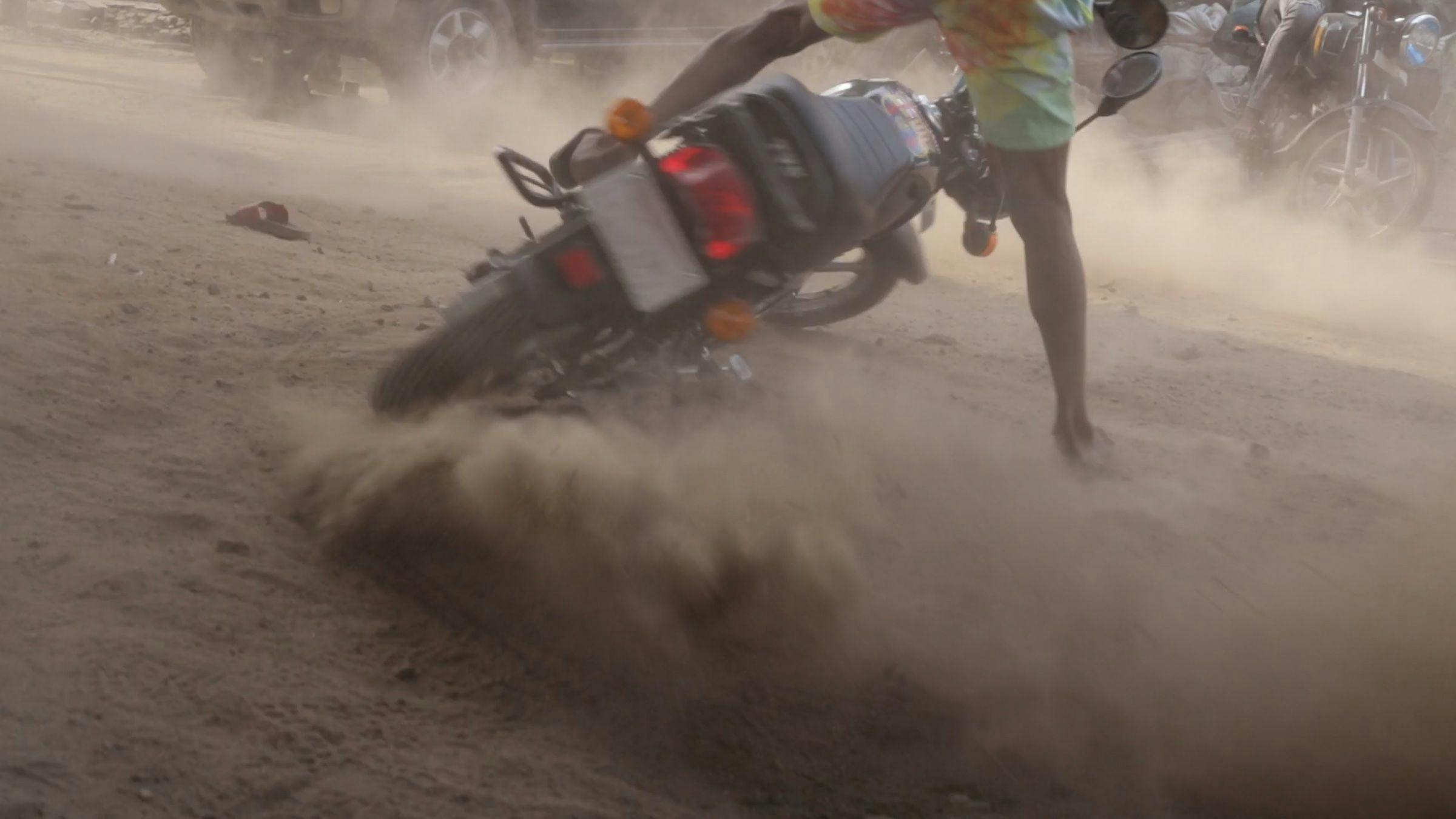 a person skidding on a motorbike. The image is blurry from the dust in the air